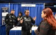 一名穿着警察制服的妇女在职业信息会上与一名学生交谈. 